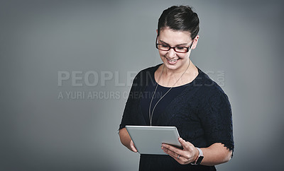 Buy stock photo Studio shot of a young businesswoman using a digital tablet against a grey background