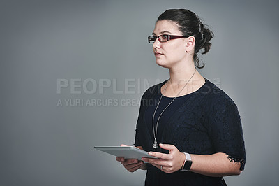 Buy stock photo Studio shot of a young businesswoman using a digital tablet against a grey background