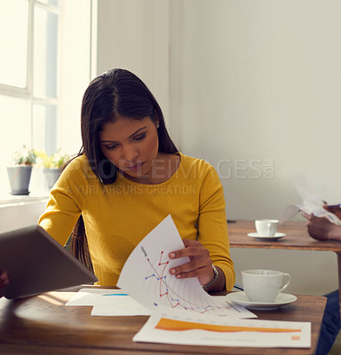 Buy stock photo Shot of a young businesswoman working through paperwork in a modern office