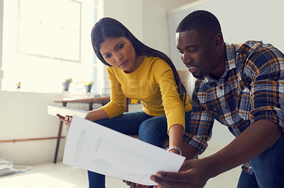 Buy stock photo Shot of a young businessman and businesswoman discussing paperwork in a modern office