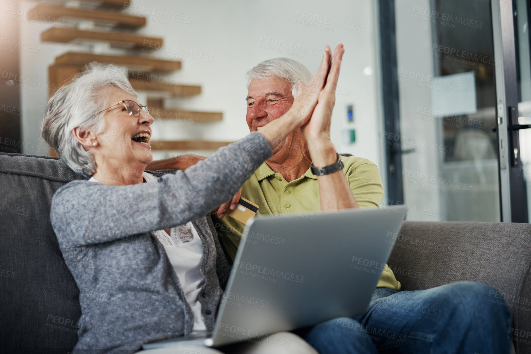 Buy stock photo Shot of a senior couple using a laptop and credit card on the sofa at home