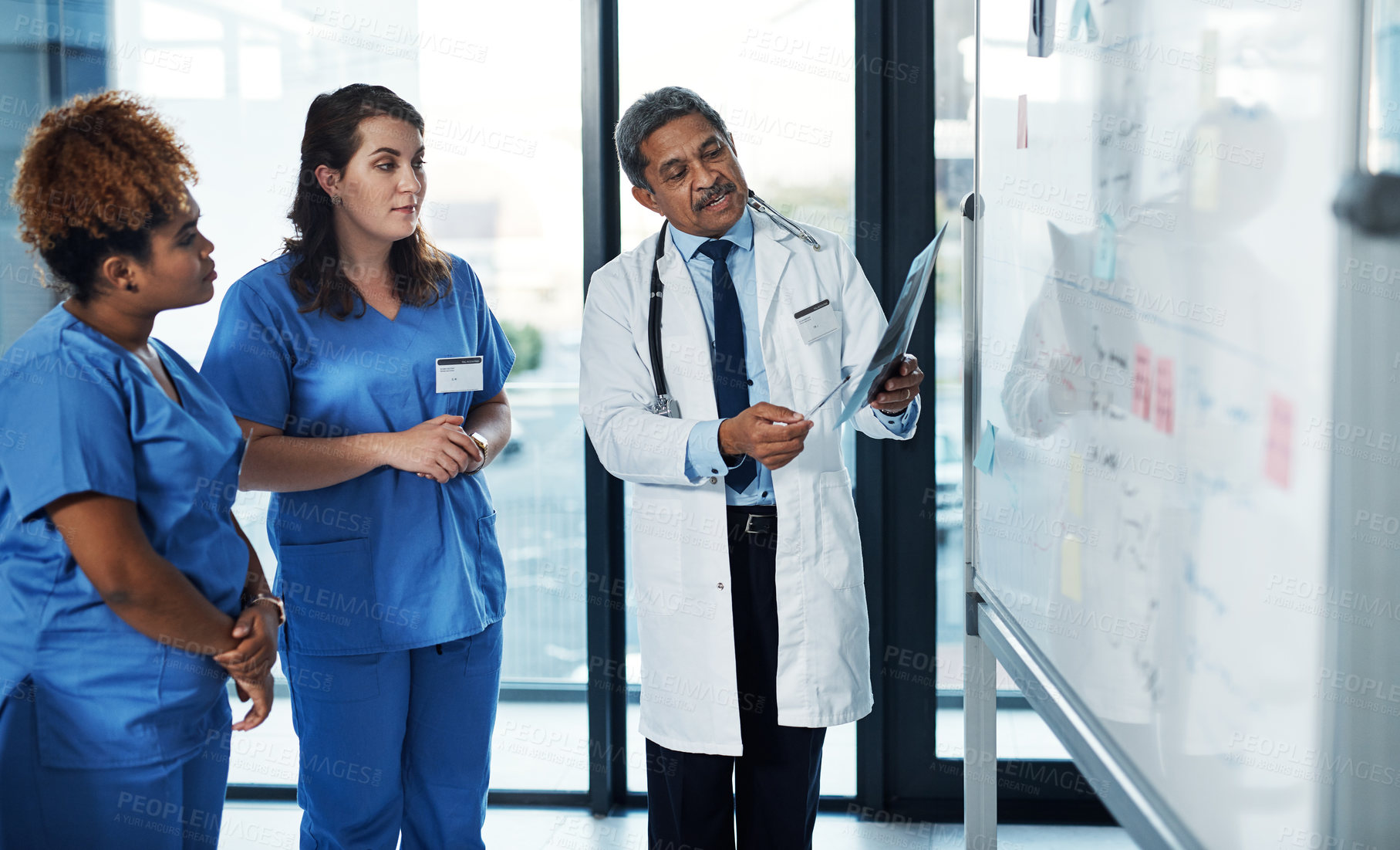 Buy stock photo Shot of a team of doctors discussing the results of an X-ray in a hospital