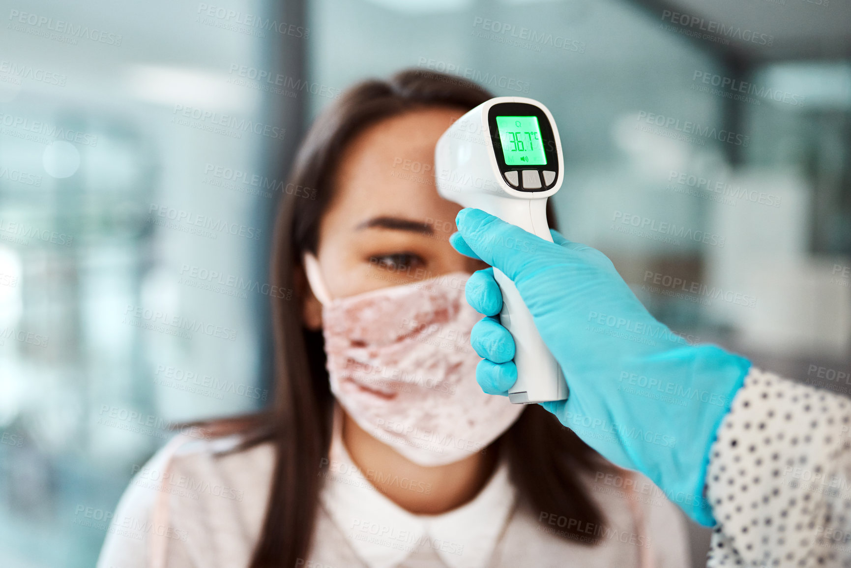 Buy stock photo Shot of a young businesswoman getting her temperature taken with an infrared thermometer in an office