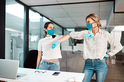 Buy stock photo Shot of two businesswomen bumping elbows in an office