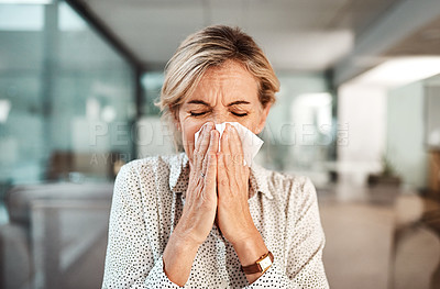 Buy stock photo Shot of a mature businesswoman blowing her nose while working in an office