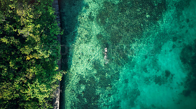 Buy stock photo High angle shot of an unrecognizable man swimming around the beautiful islands of Raja Ampat