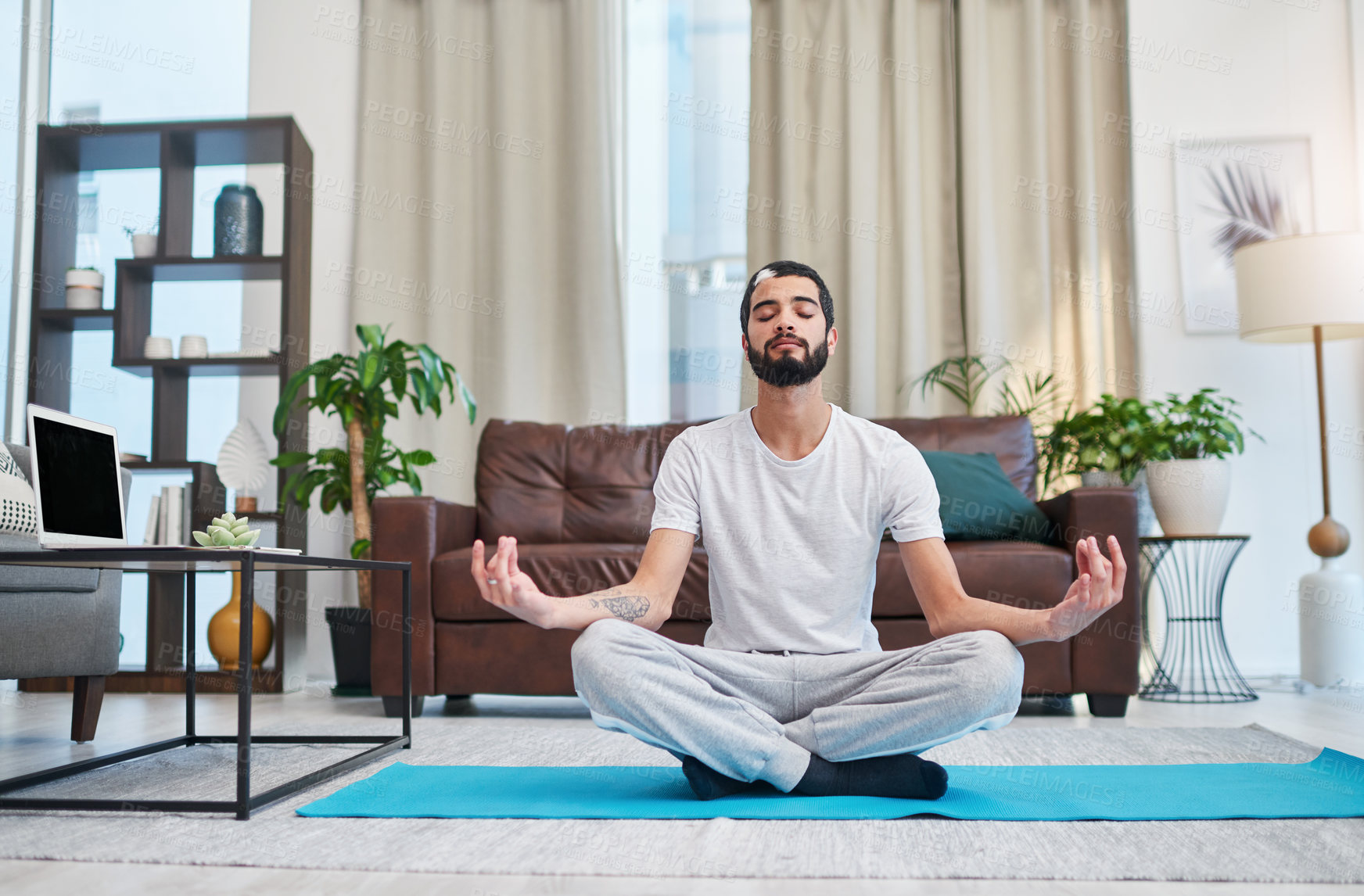 Buy stock photo Shot of a handsome young man practising yoga in his living room at home