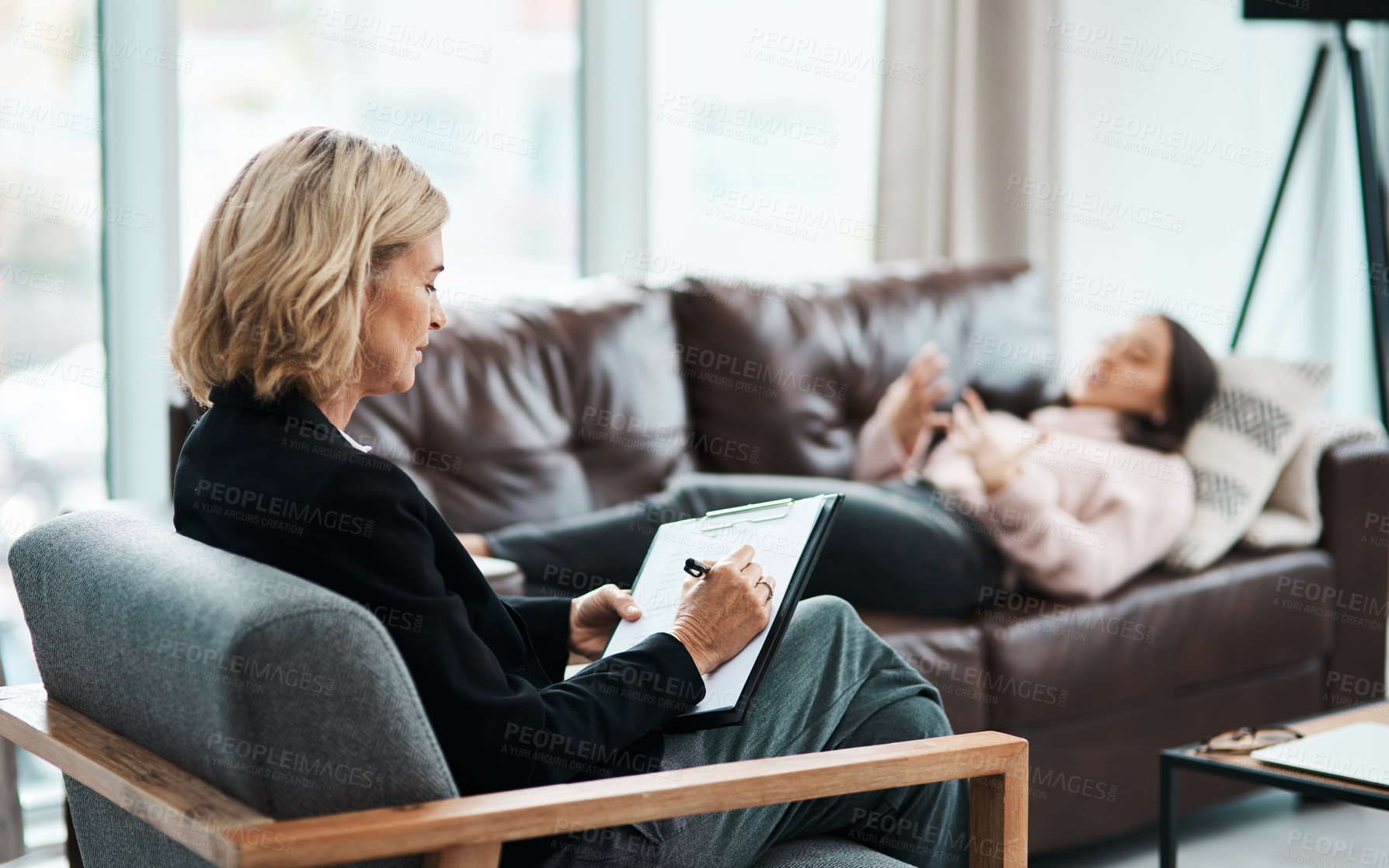 Buy stock photo Shot of a mature psychologist writing notes during a therapeutic session with her patient