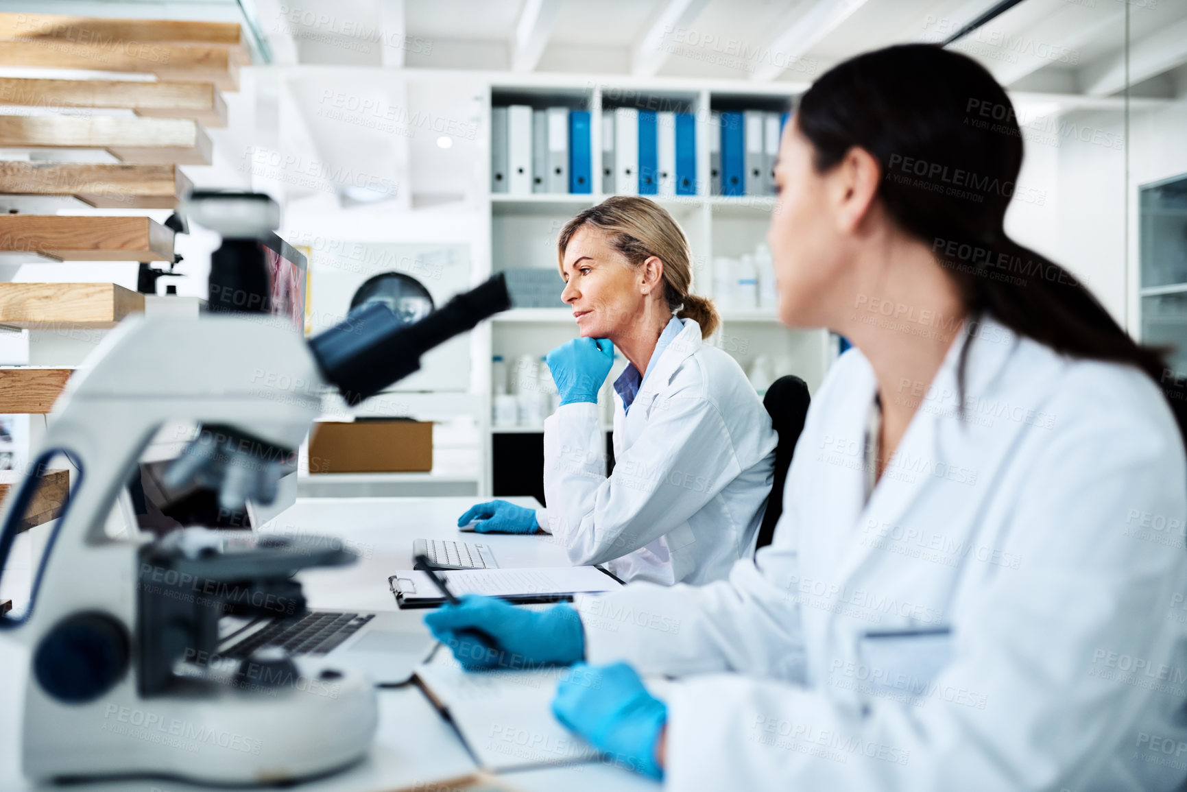 Buy stock photo Shot of a mature scientist working on a computer in a lab alongside a colleague