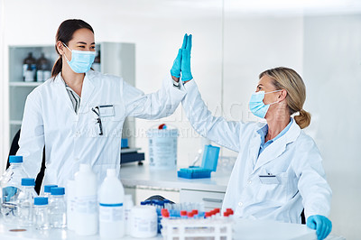 Buy stock photo Shot of two scientists giving each other a high five in a lab