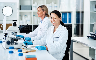 Buy stock photo Portrait of a young scientist working in a lab with her colleague in the background