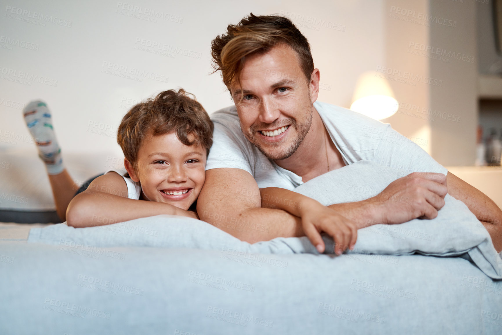 Buy stock photo Shot of a man and his son lying on a bed together