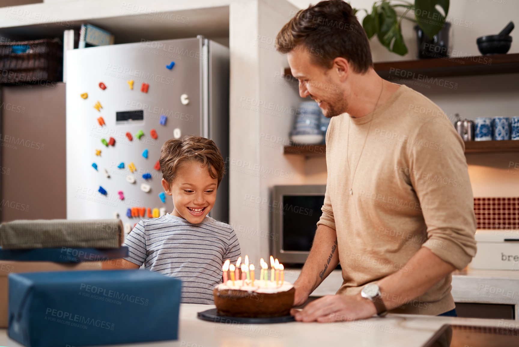 Buy stock photo Shot of a young boy looking happy while celebrating his birthday with his dad