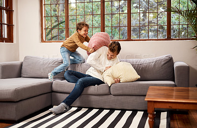 Buy stock photo Shot of a man and his young son having a pillow fight on the sofa at home