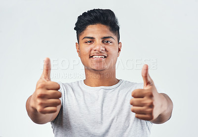 Buy stock photo Studio shot of a young man showing thumbs up while standing against a white background