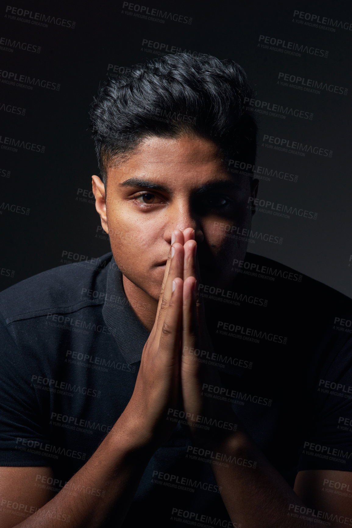 Buy stock photo Studio shot of a handsome young man sitting against a black background