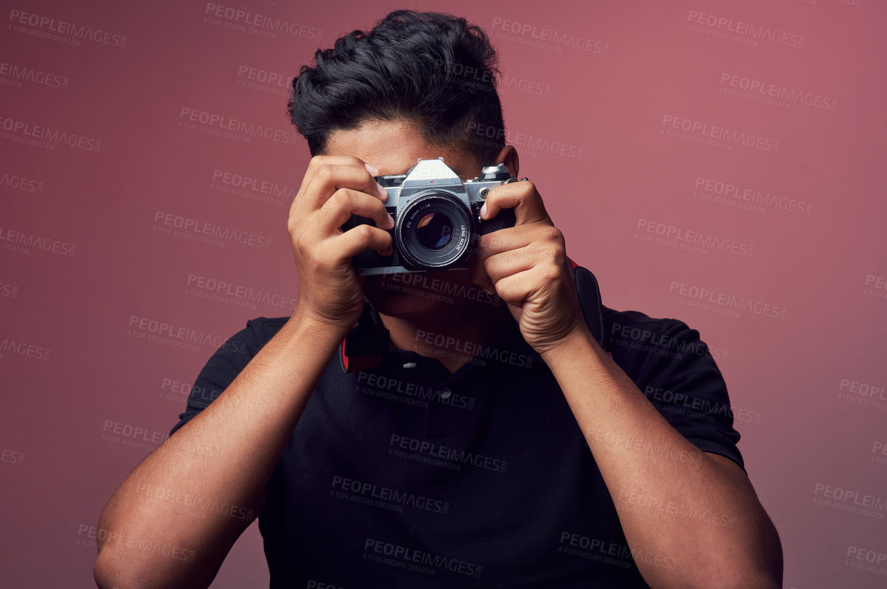Buy stock photo Studio shot of a young man holding up a camera