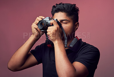 Buy stock photo Studio shot of a young man holding up a camera