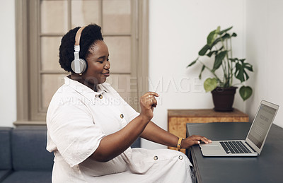 Buy stock photo Shot of a young businesswoman using headphones and a laptop in an office