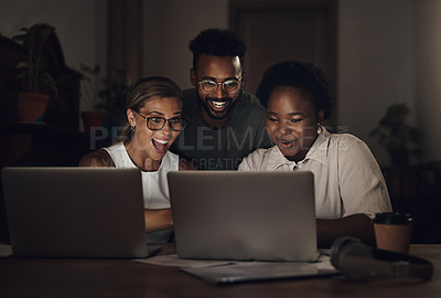 Buy stock photo Shot of a group of young businesspeople looking excited while using a laptop during a late night at work