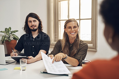 Buy stock photo Shot of a group of businesspeople going through paperwork during a meeting in an office
