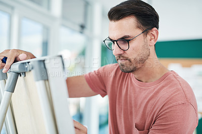 Buy stock photo Shot of a young businessman using a whiteboard during a brainstorming session in a modern office