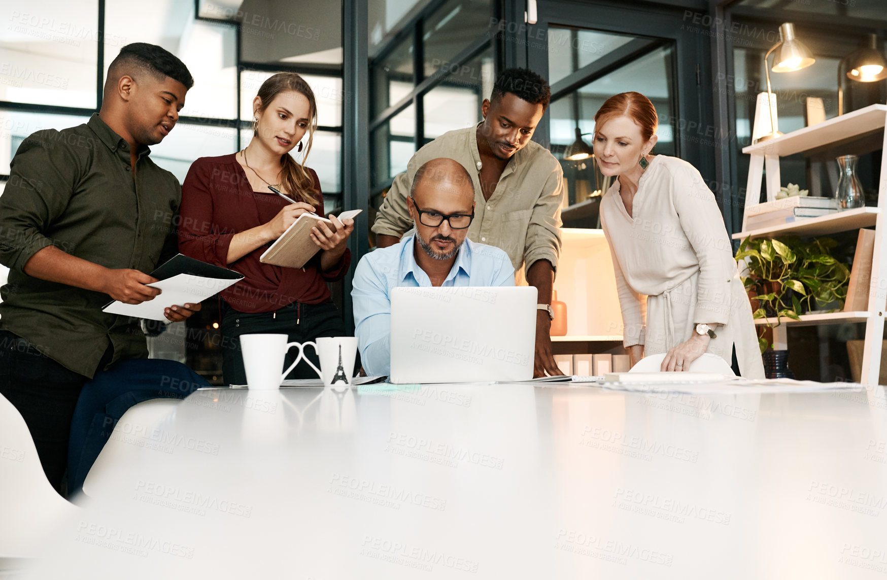 Buy stock photo Shot of a group of businesspeople using a laptop during a meeting in a modern office