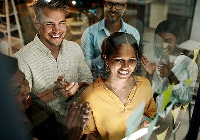 Buy stock photo Shot of a group of businesspeople using a digital tablet during a late night brainstorming session in a modern office