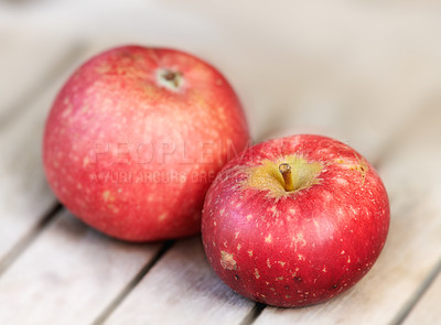 Buy stock photo Two red apples on a wooden table indoors. Eat healthy and watch your diet. Fruit contains essential vitamins to boost your immunity. Closeup of a delicious snack vegans and vegetarians can enjoy
