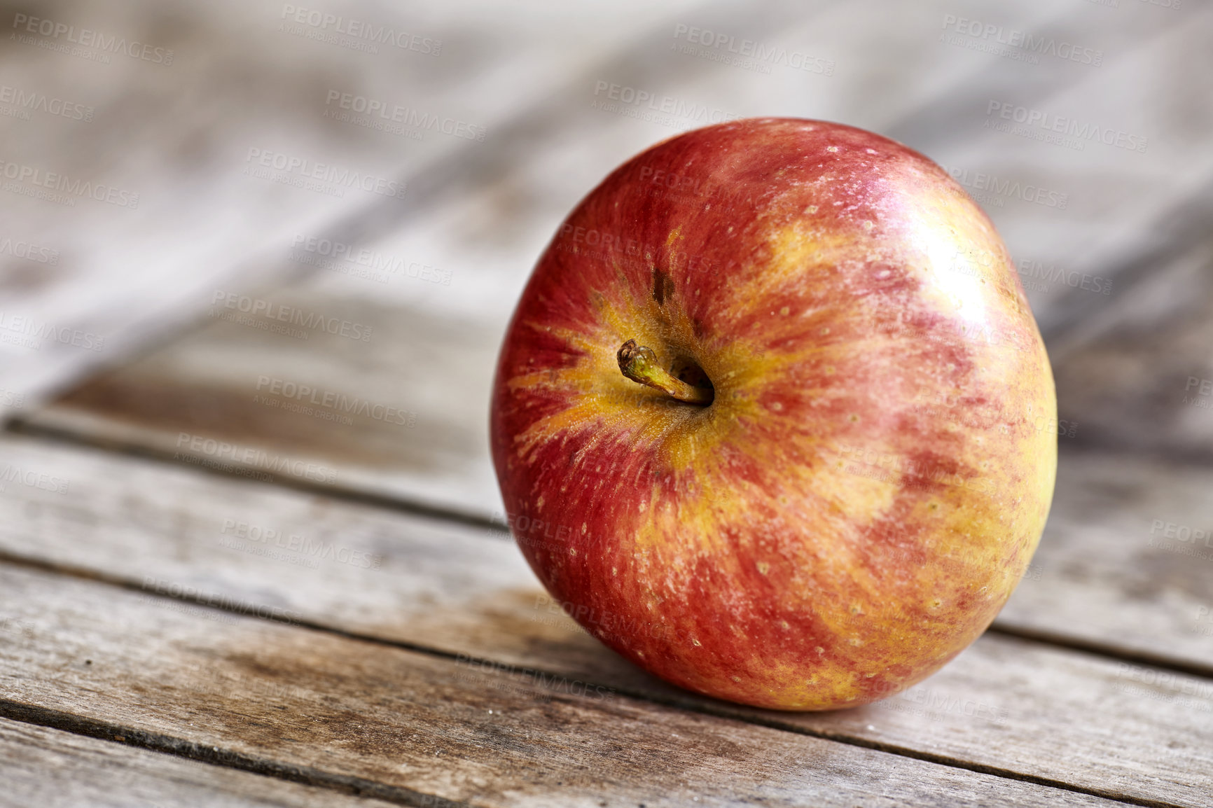 Buy stock photo A delicious, ripe red fruit on a table picked during summer harvesting season for a vegetarian, vegan friendly or healthy lifestyle. Closeup of one fresh harvested apple with copy space