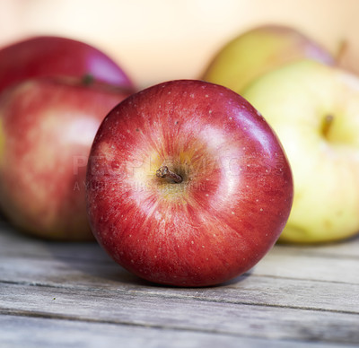 Buy stock photo Closeup of fresh red apples on a table. Delicious and organic fruit picked when ripe and in season to enjoy with vitamins for a healthy immunity. Nutritious produce for a vegan or vegetarian diet
