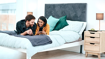 Buy stock photo Shot of a young couple using a smartphone together on their bed at home