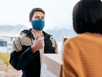 Buy stock photo Shot of a masked young man showing thumbs up while delivery a package to a customer at home