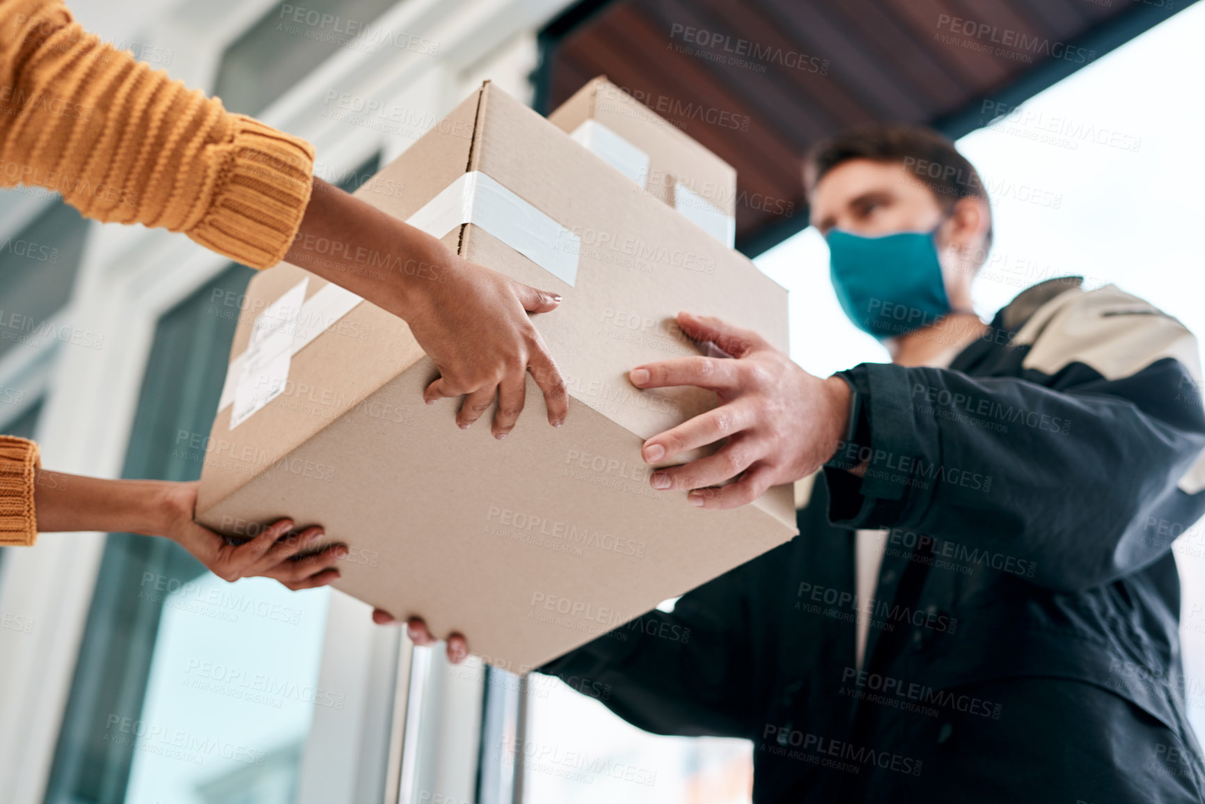 Buy stock photo Shot of a masked young man delivery a package to a woman at home