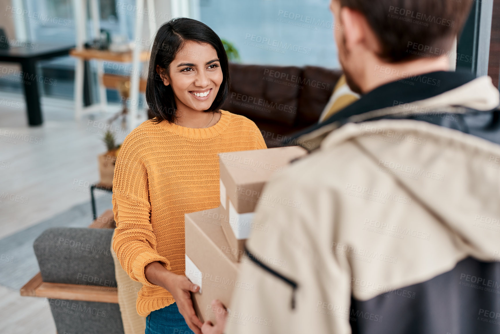 Buy stock photo Shot of a young woman receiving a package from a delivery man at home