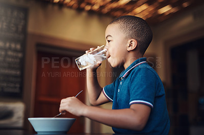 Buy stock photo Shot of a young boy drinking water with his food at home