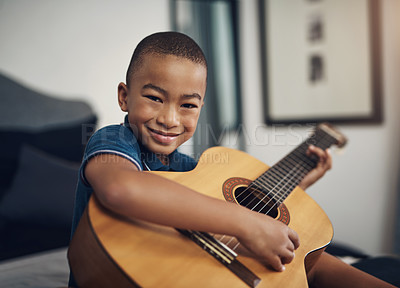 Buy stock photo Shot of a young boy playing the guitar at home