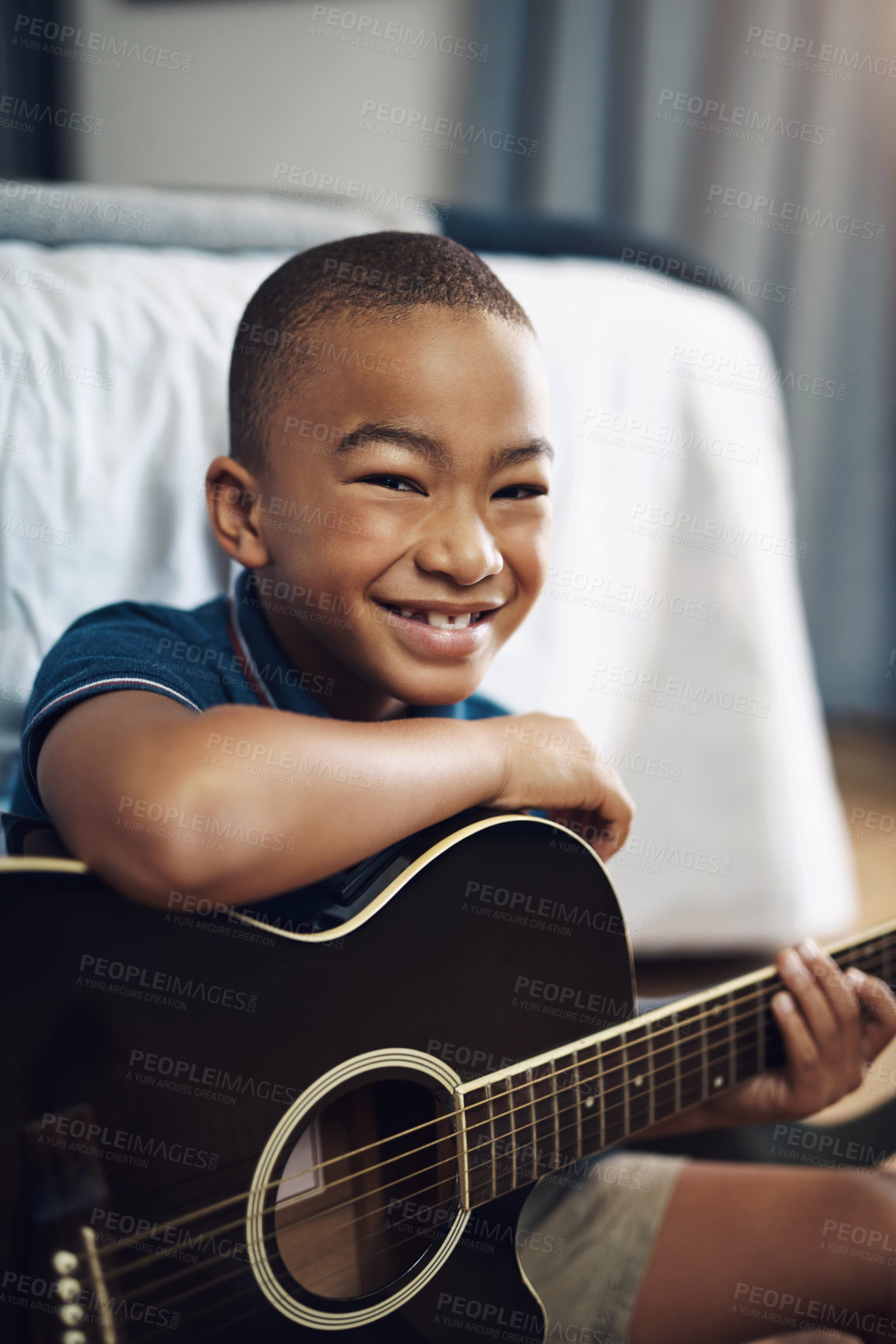 Buy stock photo Shot of a young boy playing the guitar at home