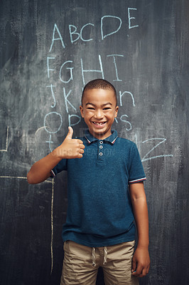 Buy stock photo Shot of a young boy showing thumbs up after writing the alphabet on a blackboard