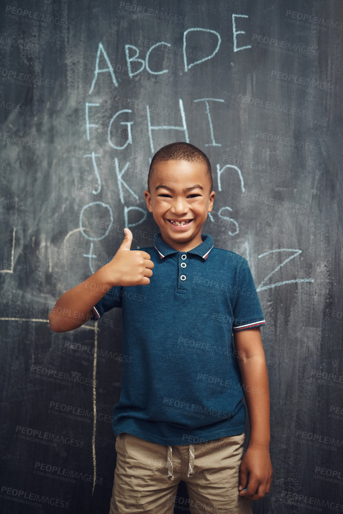 Buy stock photo Shot of a young boy showing thumbs up after writing the alphabet on a blackboard