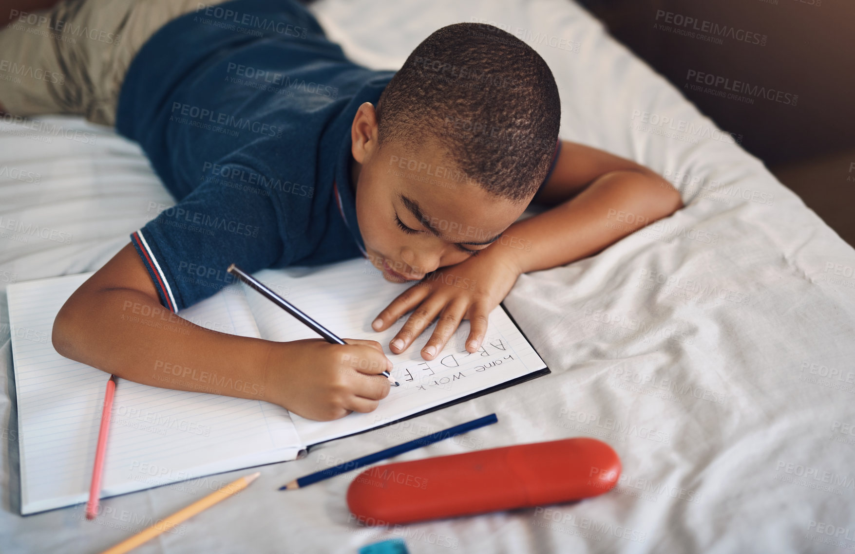 Buy stock photo Shot of a young boy using a pencil while writing at home