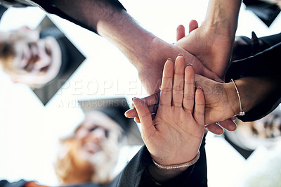 Buy stock photo Low angle shot of a group of students holding their hands together in a huddle on graduation day