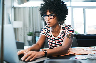 Buy stock photo Shot of a young designer using her laptop while working from home