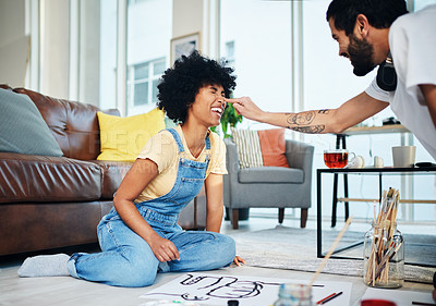 Buy stock photo Shot of a playful couple having fun while painting at home