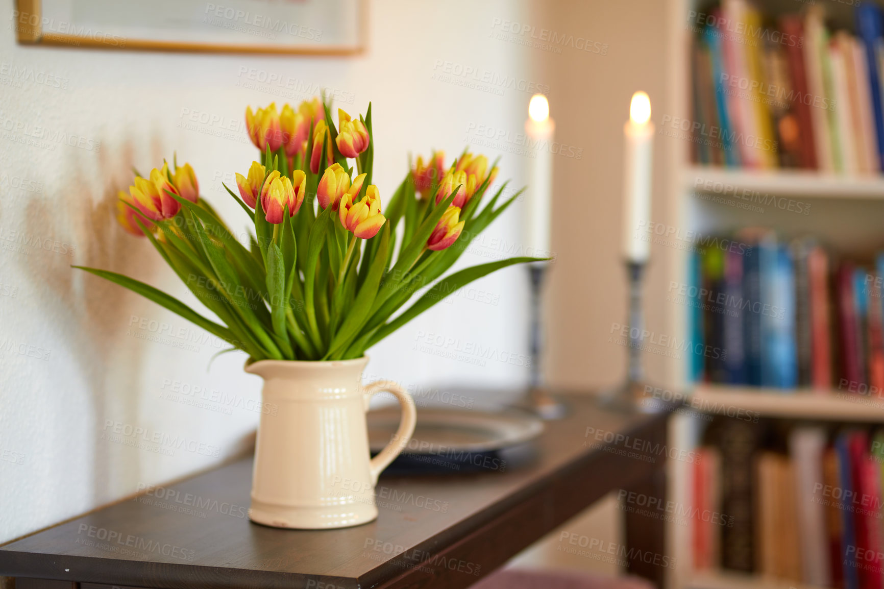 Buy stock photo Bouquet of yellow tulips in a vase as a living room decoration or centrepiece symbolising love, affection or caring gesture. Bunch of freshly cut flowers on a wooden table in a home library or study
