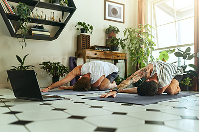 Buy stock photo Shot of two men using a laptop while going through a yoga routine at home