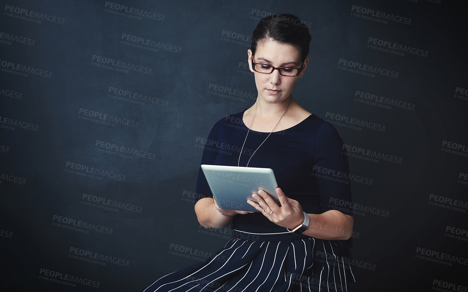 Buy stock photo Studio portrait of a corporate businesswoman using a digital tablet against a dark background