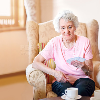 Buy stock photo Shot of a happy senior woman looking at her cards during a game with her friends in a retirement home