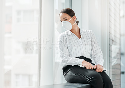 Buy stock photo Shot of a masked young businesswoman looking out of a window in a modern office