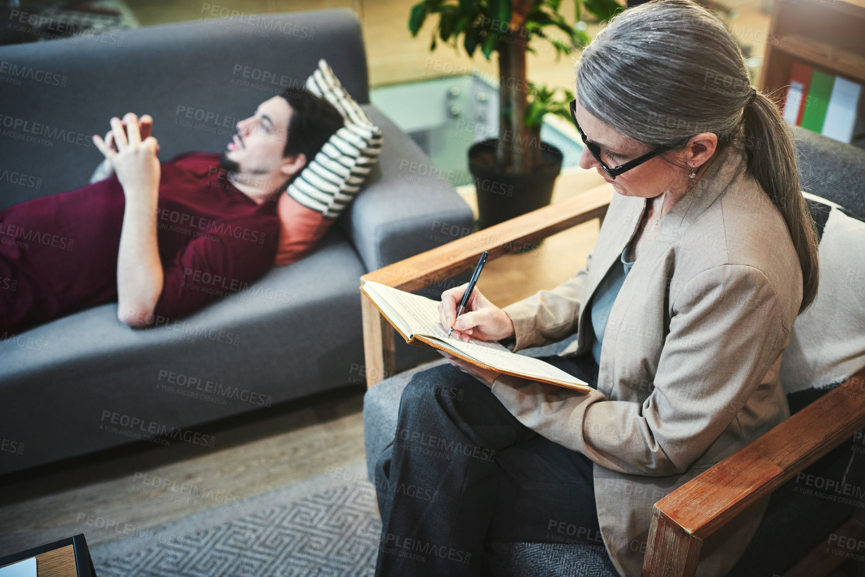 Buy stock photo Psychologist, man and patient on sofa for consultation with mental health support, writing notes and trauma treatment. Doctor, person and relax on couch for counseling, depression or advice in office